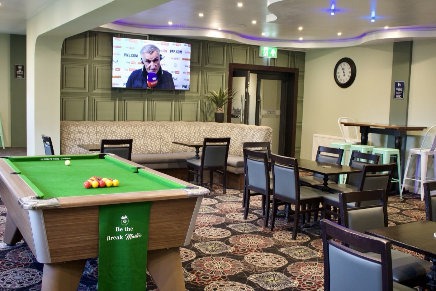 Sports lounge with big screen TV showing football and match pool table